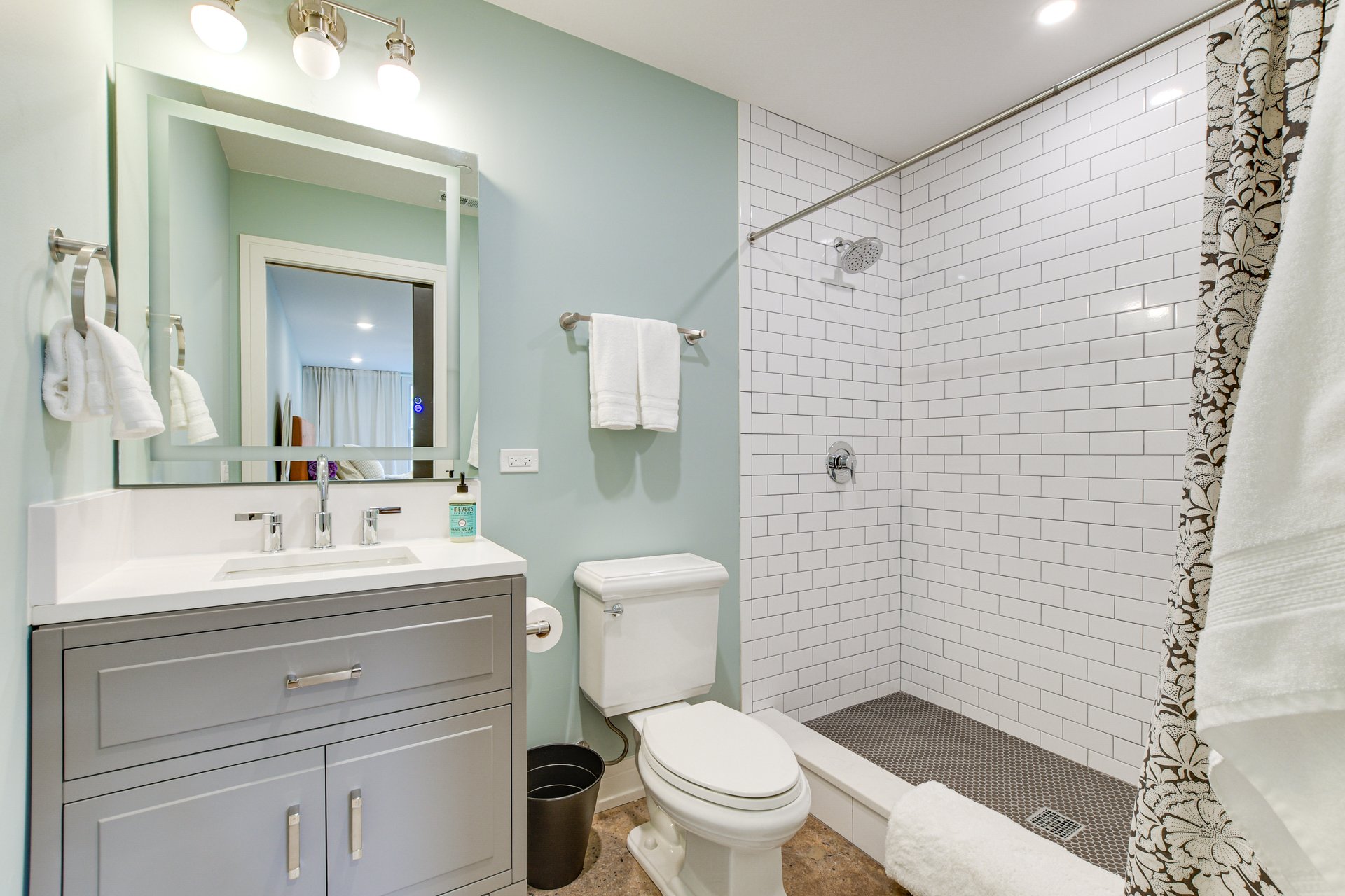 Bathroom with a subway-tiled walk-in shower and a gray vanity