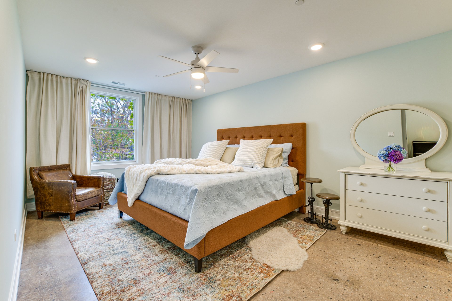 Primary bedroom with an upholstered bed and a leather reading chair